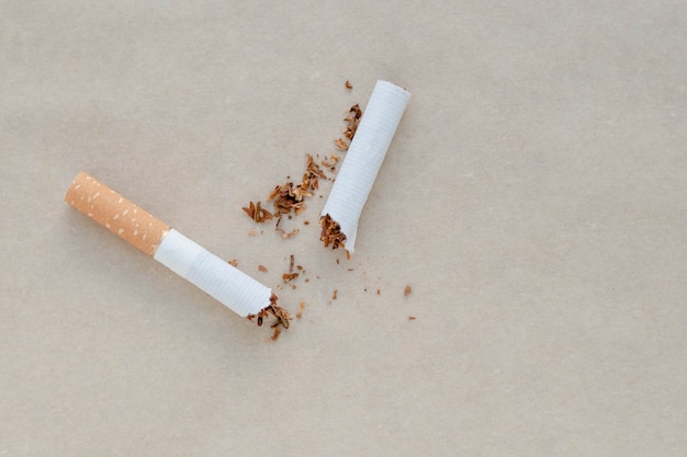 Una sigaretta rotta su uno sfondo di carta. Tabacco sparso.