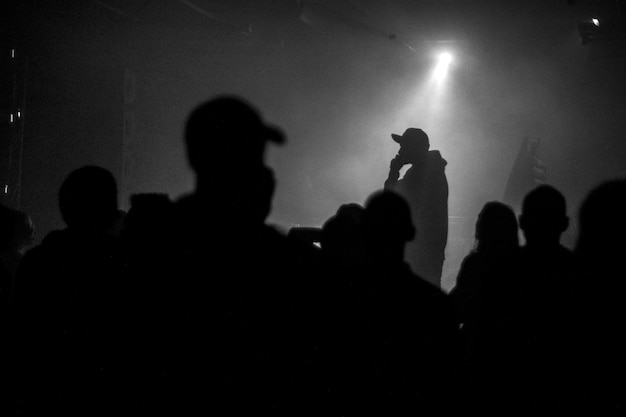 Una silhouette di cantante rap musicista durante il concerto dal vivo in condizioni di luce scura.