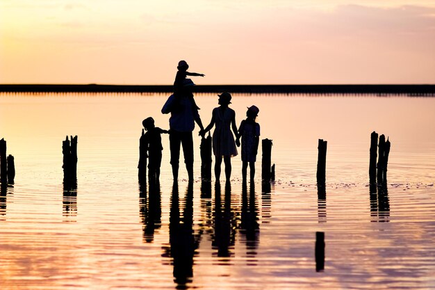 Una silhouette di famiglia felice in mare con riflesso nel parco in natura