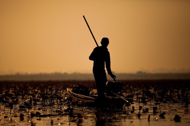 Una silhouette di un pescatore locale che prende una barca da pesca