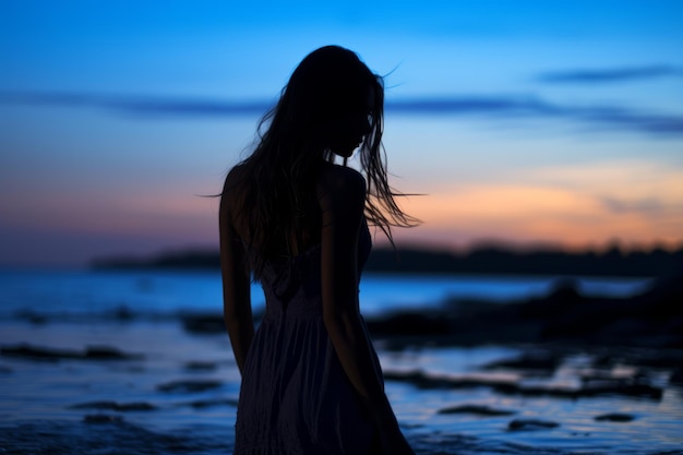 una silhouette di una donna in piedi sulla spiaggia al tramonto