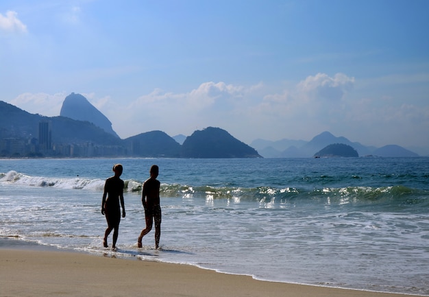 Una siluetta di una ragazza due che cammina sulla spiaggia soleggiata