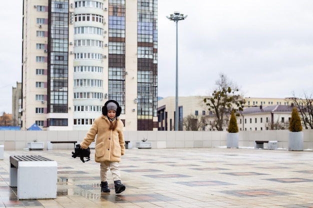 una simpatica bambina di sei anni passeggia per la piazza della città con in mano uno zaino
