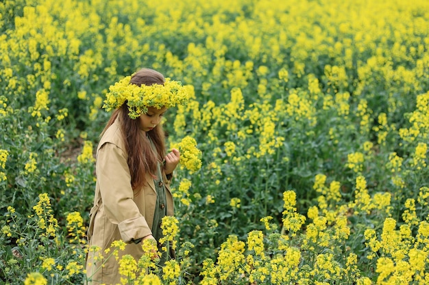 una simpatica bambina di sei anni sta in un campo di colza e raccoglie un mazzo di fiori nel villaggio