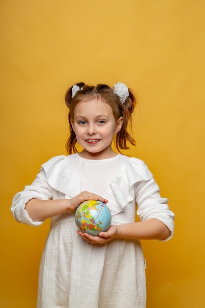 una simpatica bambina di sei anni tiene in mano un mockup della Terra e sorride