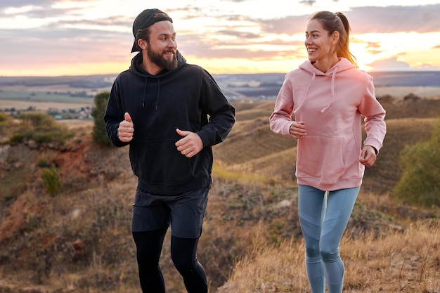 Una simpatica coppia che fa jogging insieme all'aperto, parla, si gode lo sport fuori città