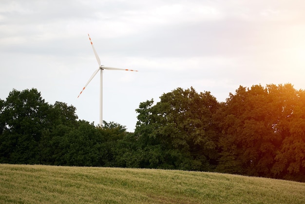 Una singola turbina eolica produce energia elettrica da energia eolica rinnovabile in un paesaggio rurale creando una silhouette contro il cielo soleggiato la turbina eolica genera energia elettrica in modo sostenibile