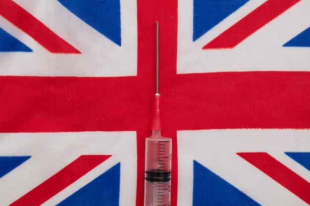 Una siringa per vaccino medico su una bandiera della presa dell'Unione del Regno Unito