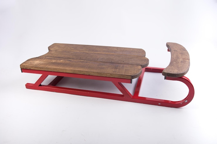 Foto una slitta rossa con sedile in legno e sedile in legno.