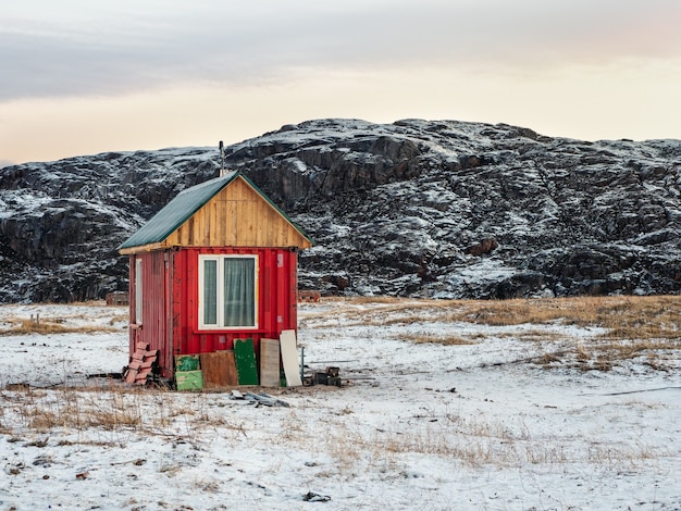 Una solitaria casa rossa autentica nella tundra artica in inverno.