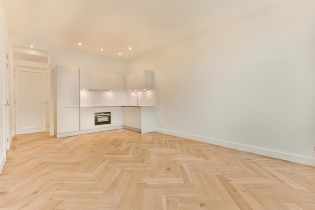 Una spaziosa camera con pavimenti in parquet e una cucina ad angolo in bianco in una casa moderna