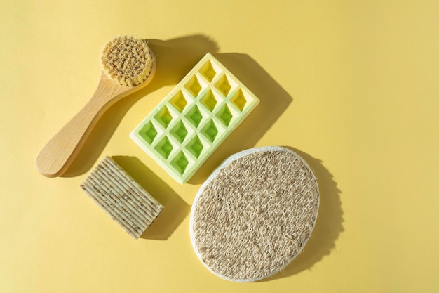 Una spazzola per la cura del corpo, un massaggiatore, un sapone naturale e una bomba da bagno per procedure termali sdraiato su uno sfondo colorato