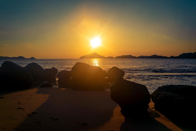 Una spiaggia al tramonto con il sole che tramonta alle sue spalle