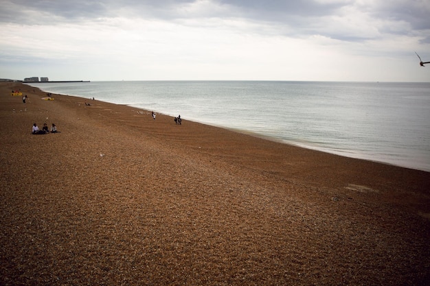 Una spiaggia con poche persone sopra e un cielo grigio sullo sfondo.