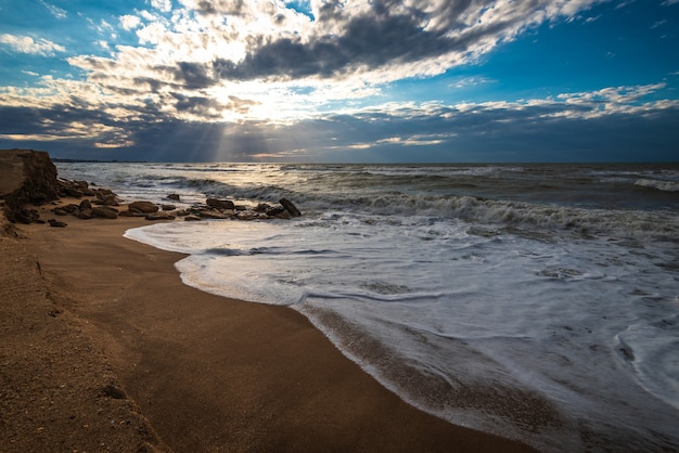 Una spiaggia con sabbia dorata, piccole onde e un bellissimo cielo drammatico