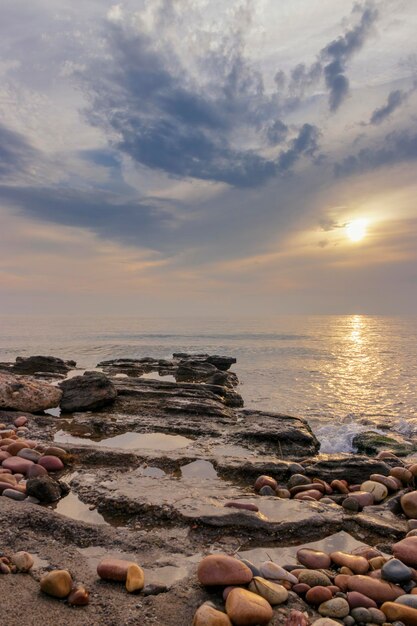 Una spiaggia con un cielo nuvoloso e un tramonto sullo sfondo