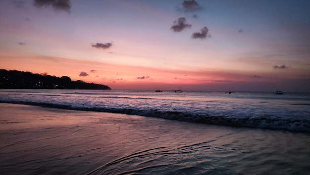 Una spiaggia con un cielo rosa e una spiaggia sullo sfondo