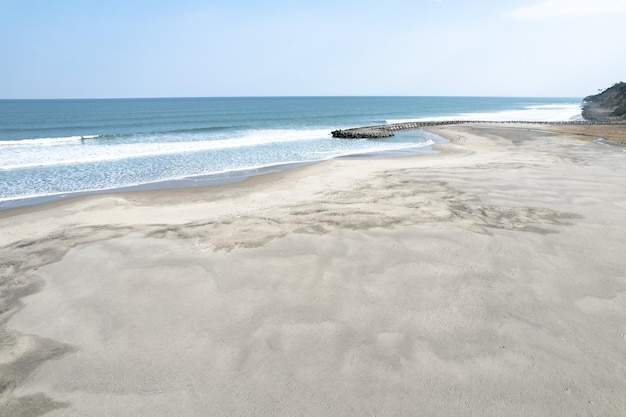 Una spiaggia con un molo sullo sfondo