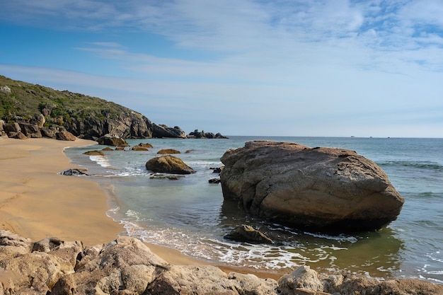 Una spiaggia con una grande roccia su di esso