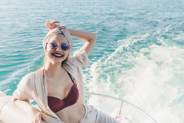 Una splendida ragazza sorridente con gli occhiali da sole si gode il viaggio per mare, naviga sul mare