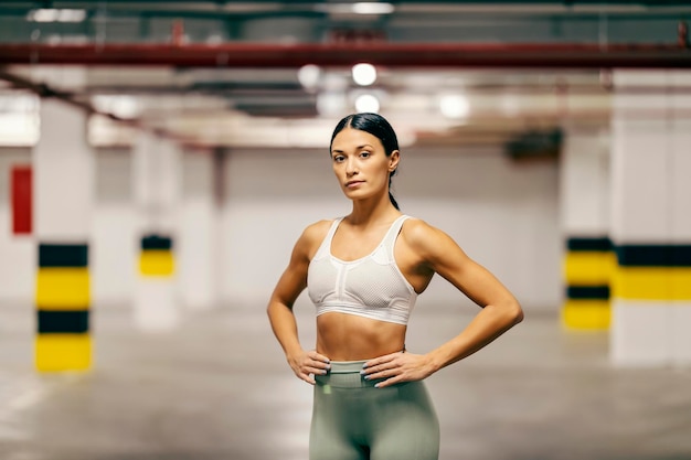 Una sportiva in forma muscolare sta posando nel garage sotterraneo