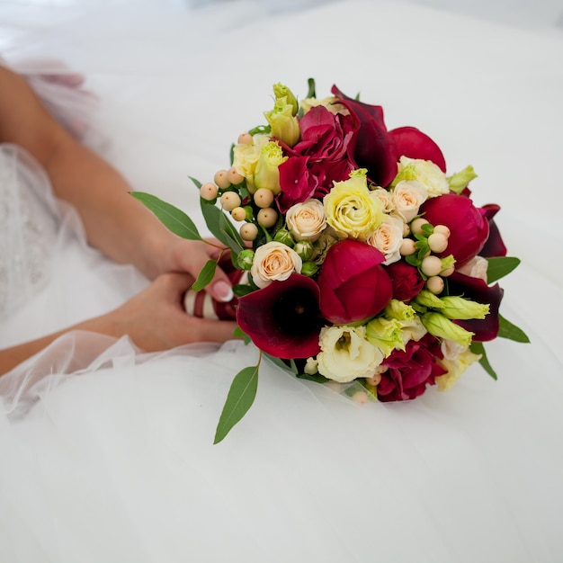 Una sposa alla moda in un bellissimo abito da sposa tiene in mano un bouquet da sposa.