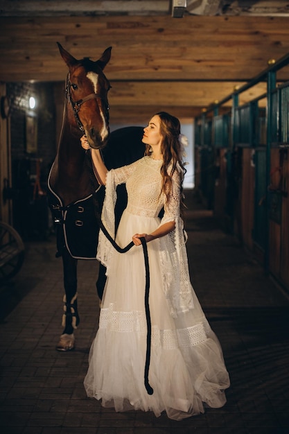 Una sposa boho posa con un cavallo in una stalla