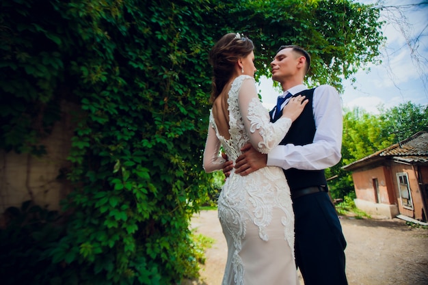 Una sposa con un taglio di capelli corto e uno sposo elegante cammina nel parco.