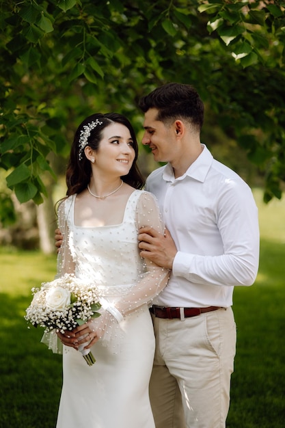 Una sposa e lo sposo posano per una foto in un parco.