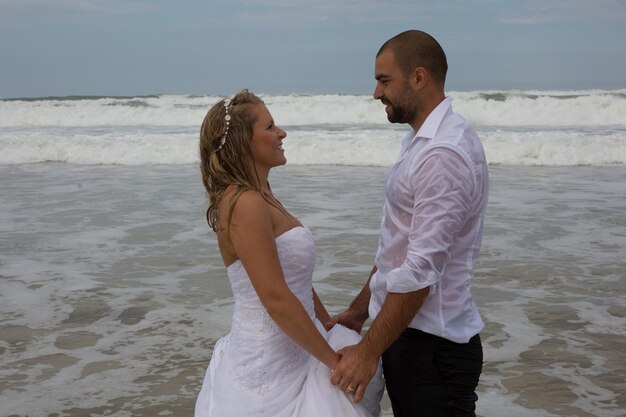 Una sposa e uno sposo attraenti che si sposano sulla spiaggia