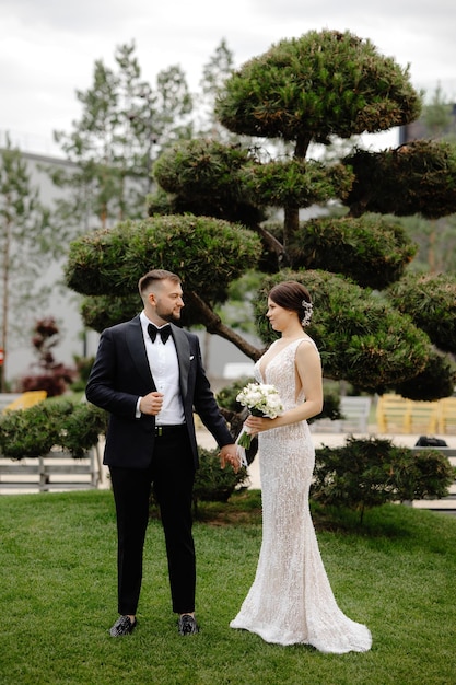 Una sposa e uno sposo camminano davanti a un albero