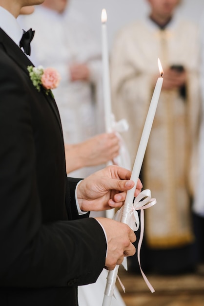 Una sposa e uno sposo che tengono le candele alla chiesa durante la cerimonia di nozze si chiuda