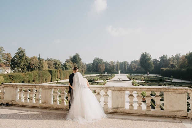 Una sposa e uno sposo si trovano in un giardino con vista sulla reggia di versailles sullo sfondo
