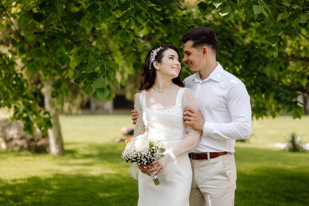 Una sposa e uno sposo sono in piedi in un parco.