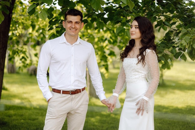 Una sposa e uno sposo stanno sotto un albero in un parco.