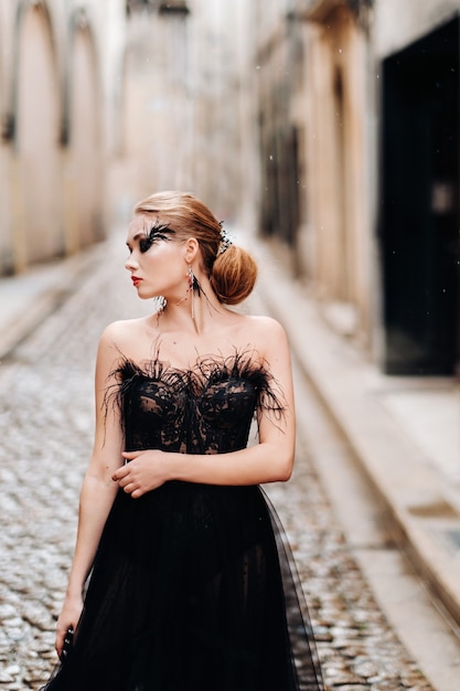 Una sposa elegante in un abito da sposa nero posa nell'antica città francese di Avignone. Modello in un bellissimo vestito nero. Servizio fotografico in Provenza.