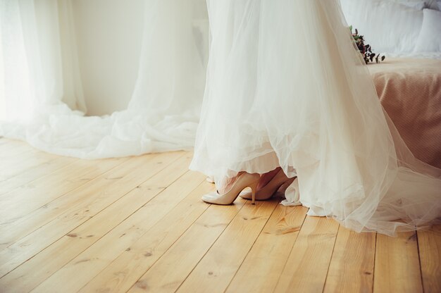 Una sposa in abito da sposa e scarpe sul pavimento di legno