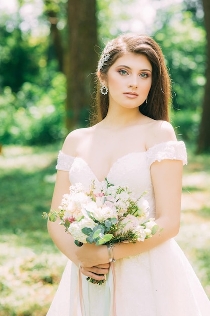 Una sposa in un tradizionale abito bianco con un bouquet da sposa accanto all'arco nuziale