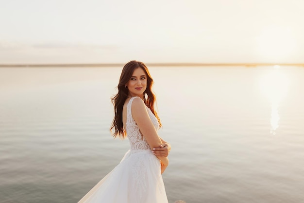 Una sposa si trova su una spiaggia di fronte a un lago