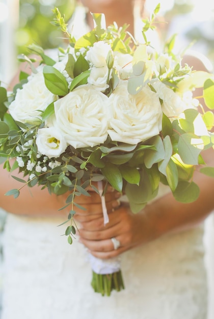 Una sposa tiene un mazzo di rose bianche.