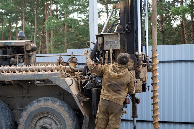 Una squadra di lavoratori con un impianto di perforazione su auto sta perforando un pozzo artesiano per l'acqua nel terreno Inserimento di un tubo di rivestimento metallico nell'installazione a terra di un approvvigionamento idrico individuale 28 giugno 2022 Russia