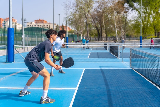 Una squadra multietnica di pickleball che gioca con gli amici in un campo all'aperto