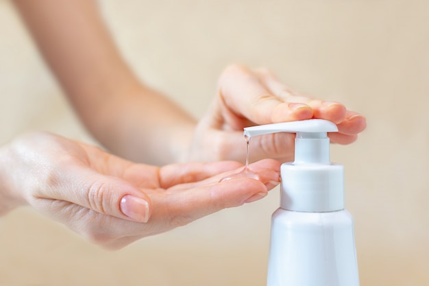 Una stampa femminile su una bottiglia con gel antibatterico per pulire e lavare le mani dei batteri. Concetto di protezione e profilassi contro la malattia di coronavirus.