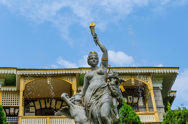 Una statua di una donna che regge una torcia si trova di fronte a un edificio con un cielo blu sullo sfondo.