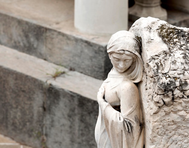 Una statua di una donna con sopra una croce