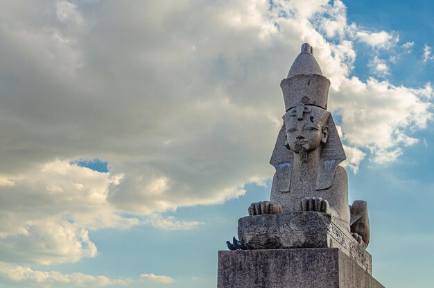 Una statua di una sfinge si trova di fronte a un cielo nuvoloso.