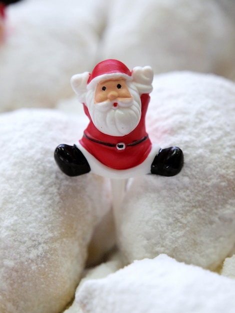 Una statuina di Babbo Natale è su una ciambella con zucchero a velo bianco.
