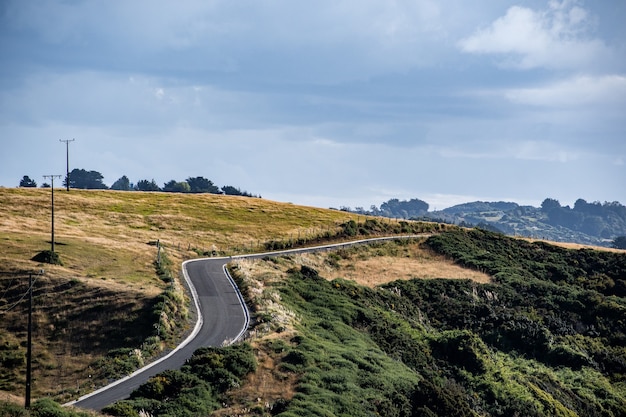 Una strada asfaltata con colline di prati in una giornata nuvolosa a Chilo