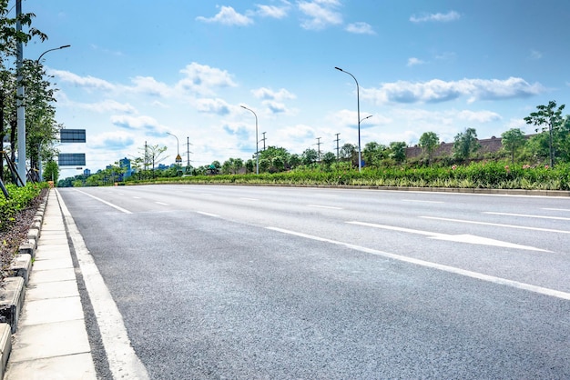 Una strada asfaltata senza auto alla periferia della città sotto un cielo blu