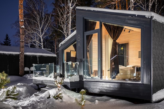 Una strada con case di legno identiche con un piccolo balcone, finestre panoramiche, una foresta invernale sullo sfondo